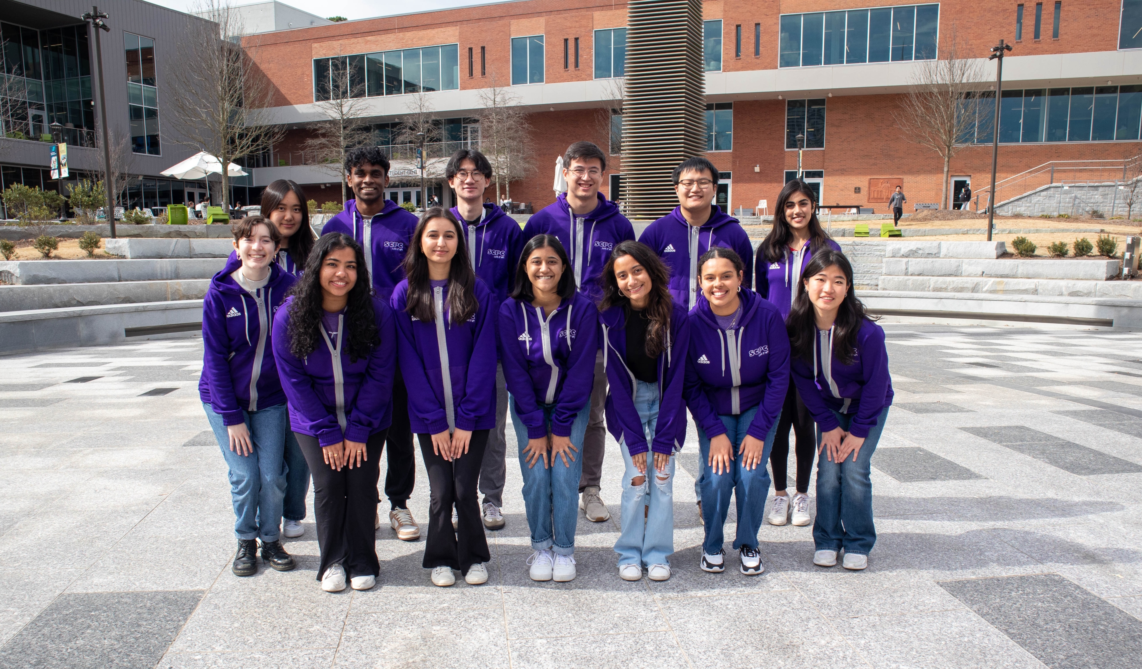 Group of students wearing purple jackets standing in front of student center