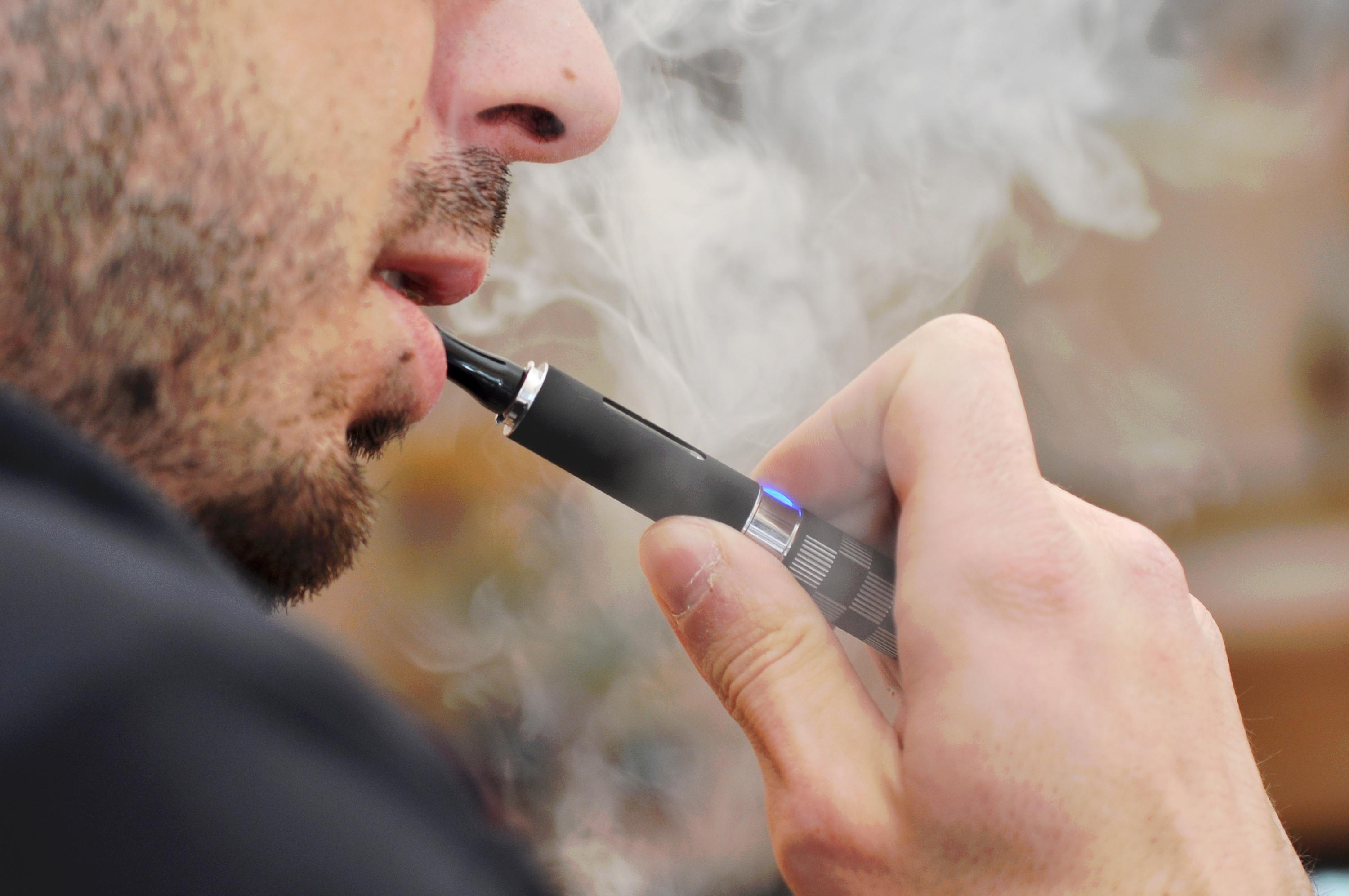 Man smoking an e-cigarette and a cloud of smoke.